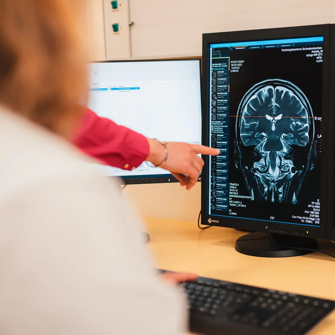 Eine Frau weist auf ein MRT-Bild, das auf einem Computerbildschirm angezeigt wird.